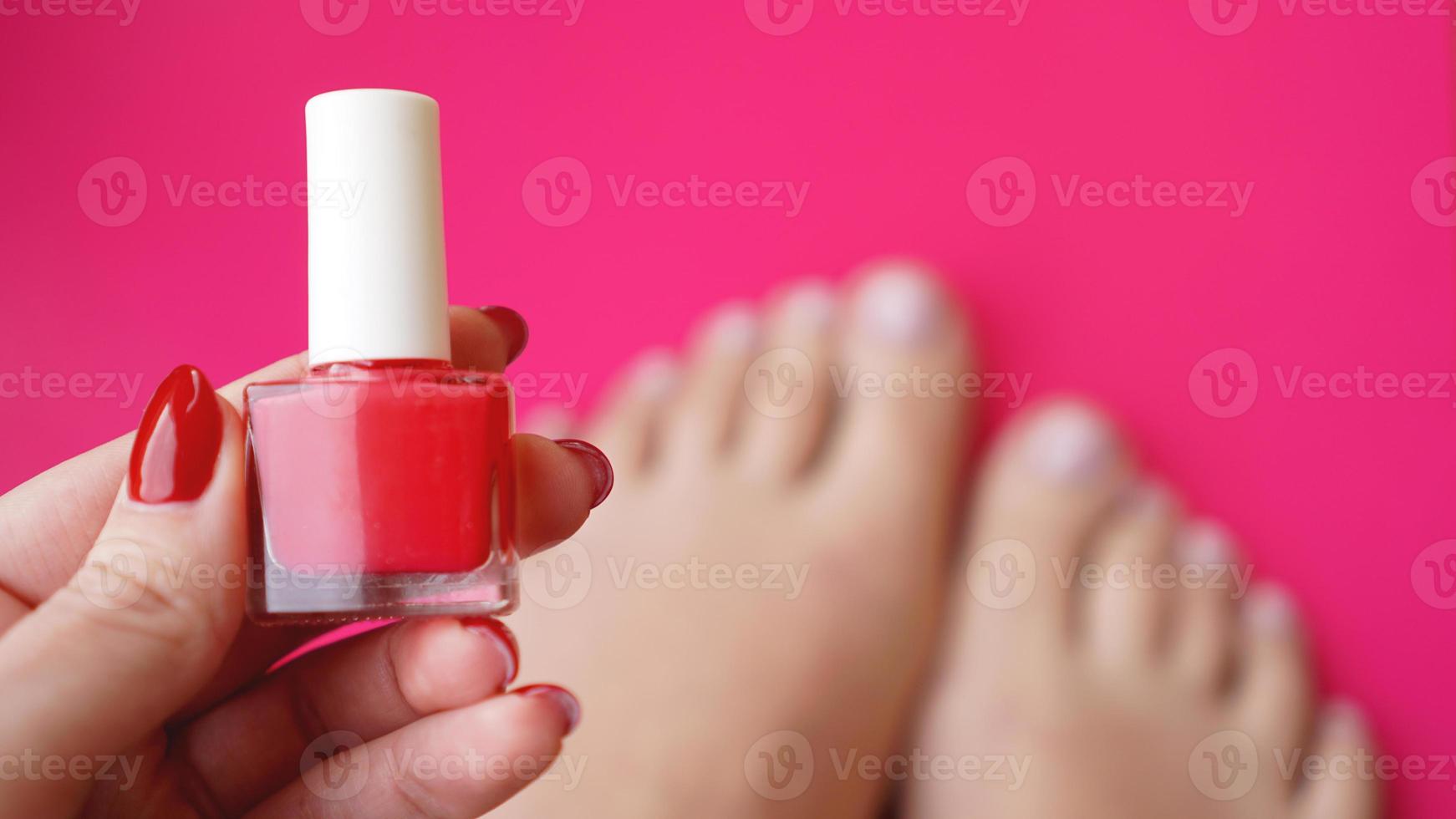 Young perfect groomed womans feet on pink background. Care about nails photo