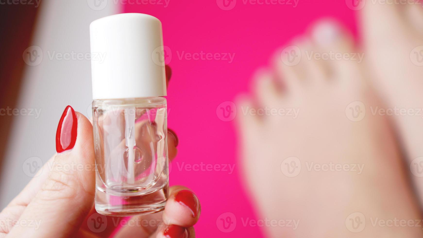 Young perfect groomed womans feet on pink background. Care about nails photo