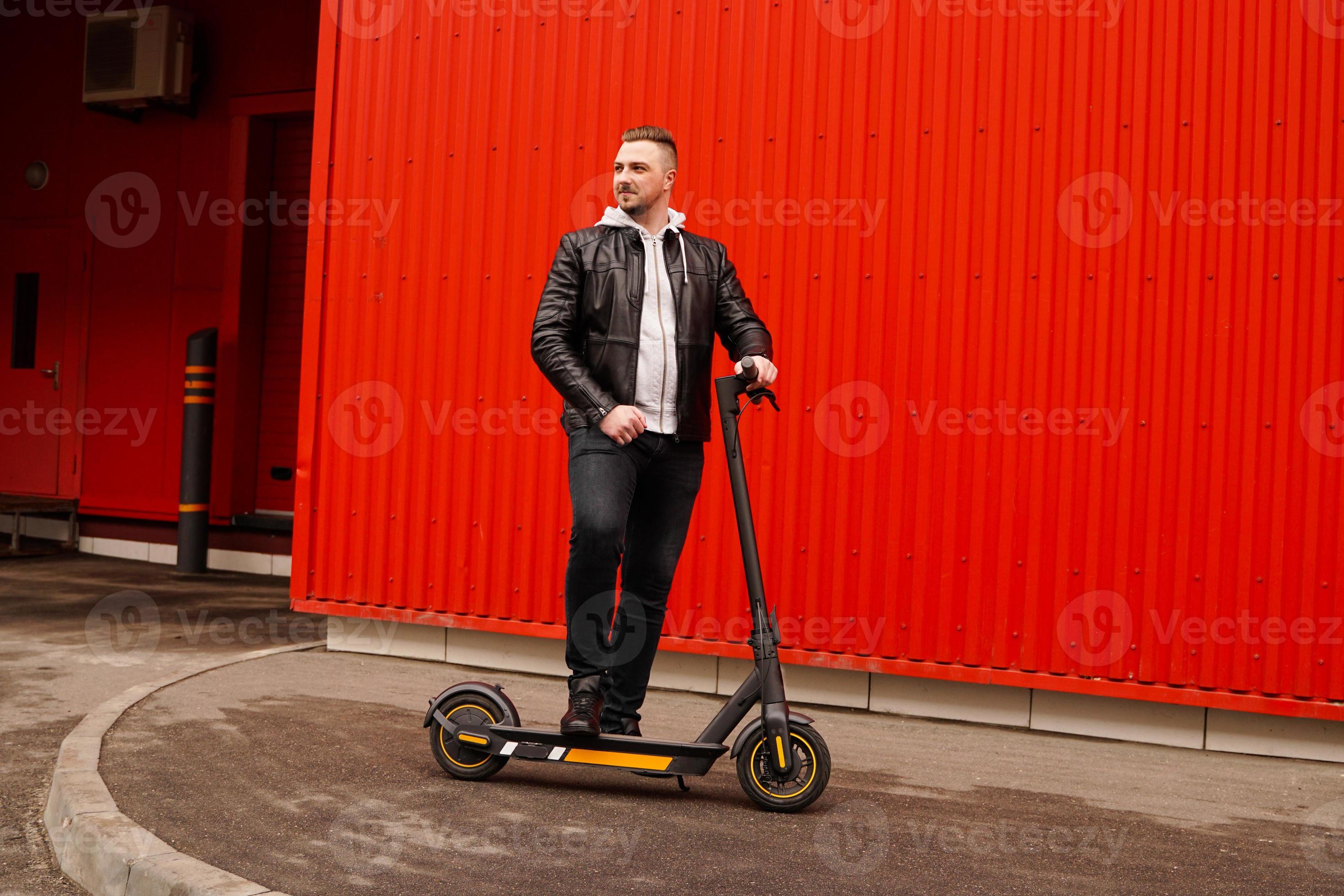 Young attractive man on electric scooter over red background 3259260