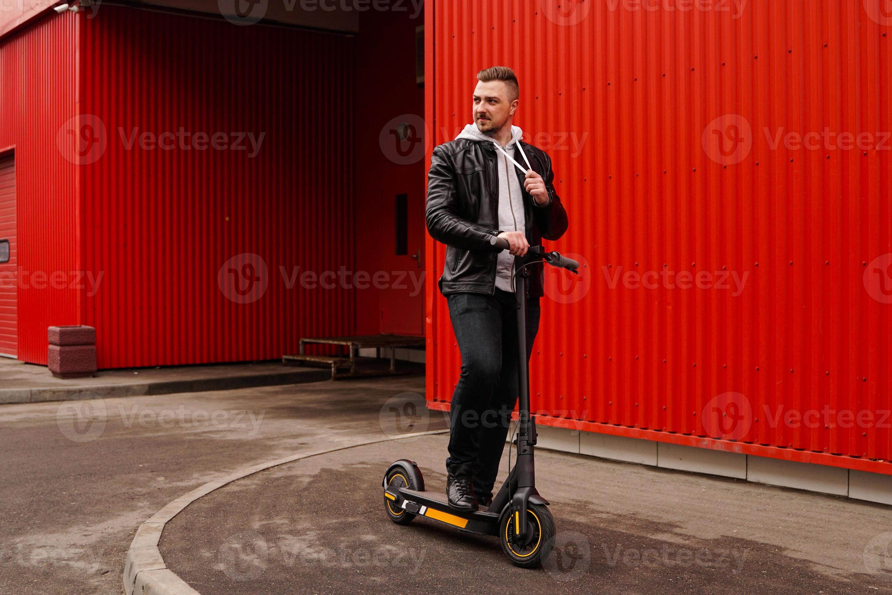 Young attractive man on electric scooter over red background 3259262