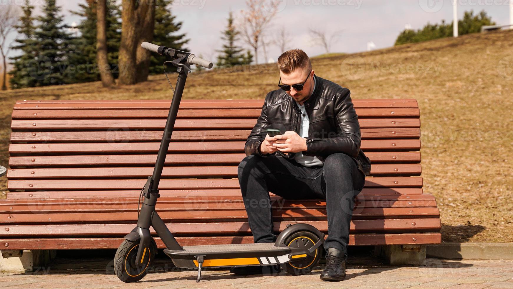 Young man sits on a bench on a spring day photo