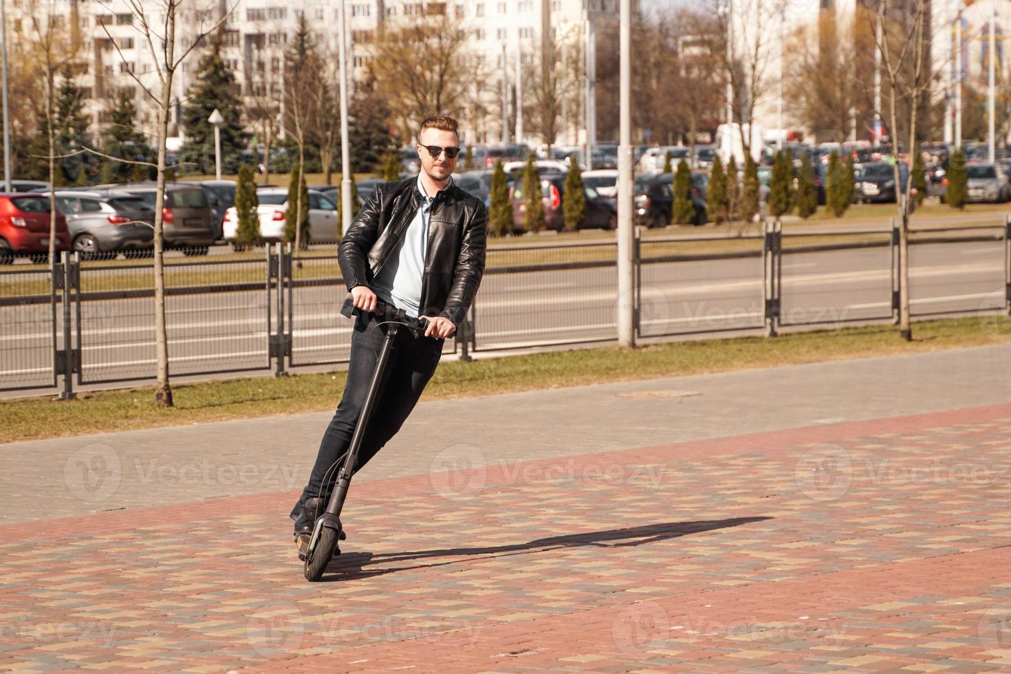 Hombre moderno montando scooter eléctrico en la ciudad foto