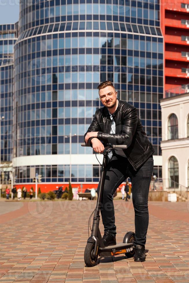 Innovative transport. Glad optimistic guy leaning on electric scooter photo