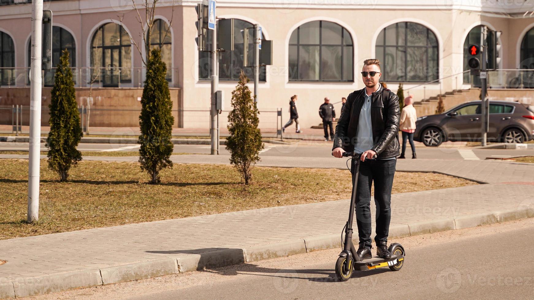 Modern man riding electric scooter in the city photo