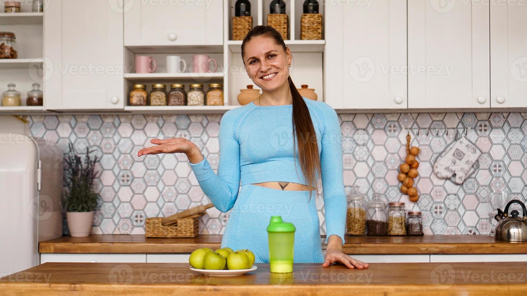 Athletic woman talks about healthy eating in the kitchen and laughs photo