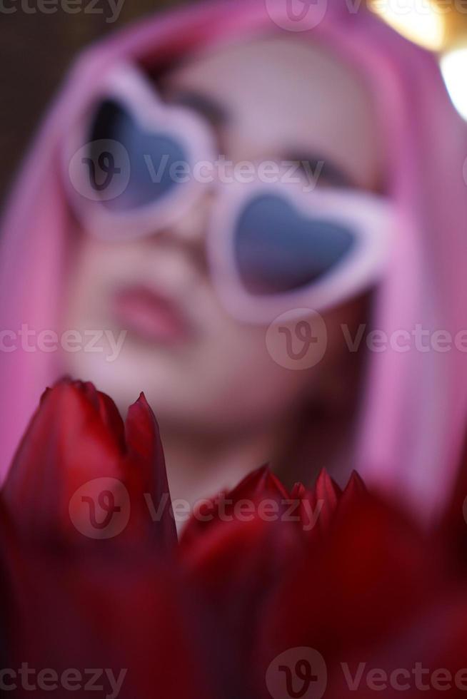 Girl with pink hair with flowers close to face photo