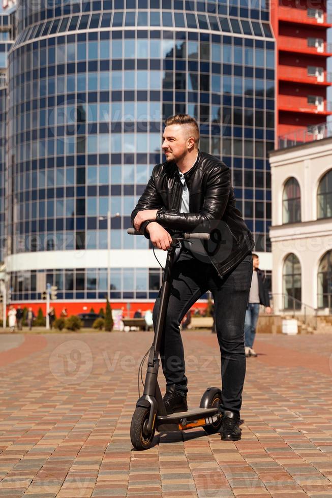 Innovative transport. Glad optimistic guy leaning on electric scooter photo