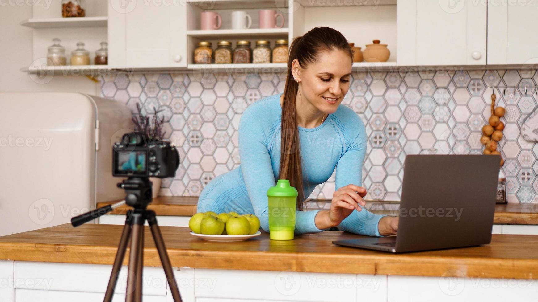 Woman in kitchen with laptop looking recipes photo