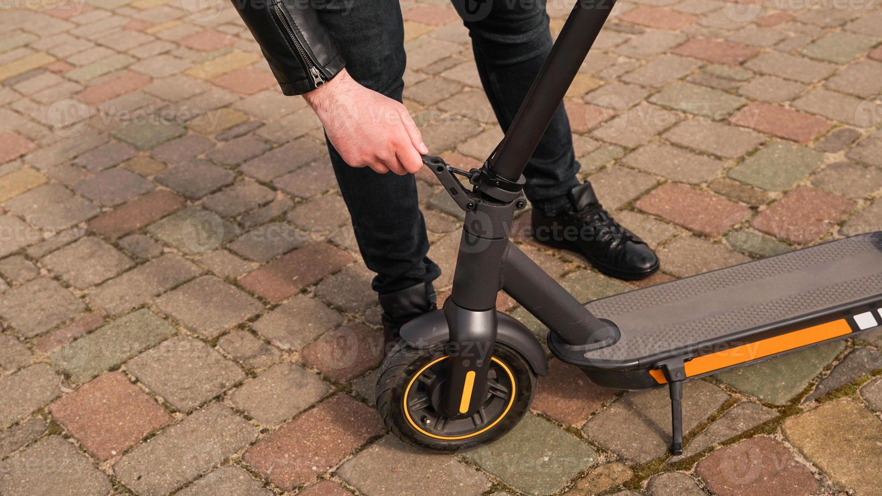 joven plegable un scooter eléctrico en la calle al aire libre. foto