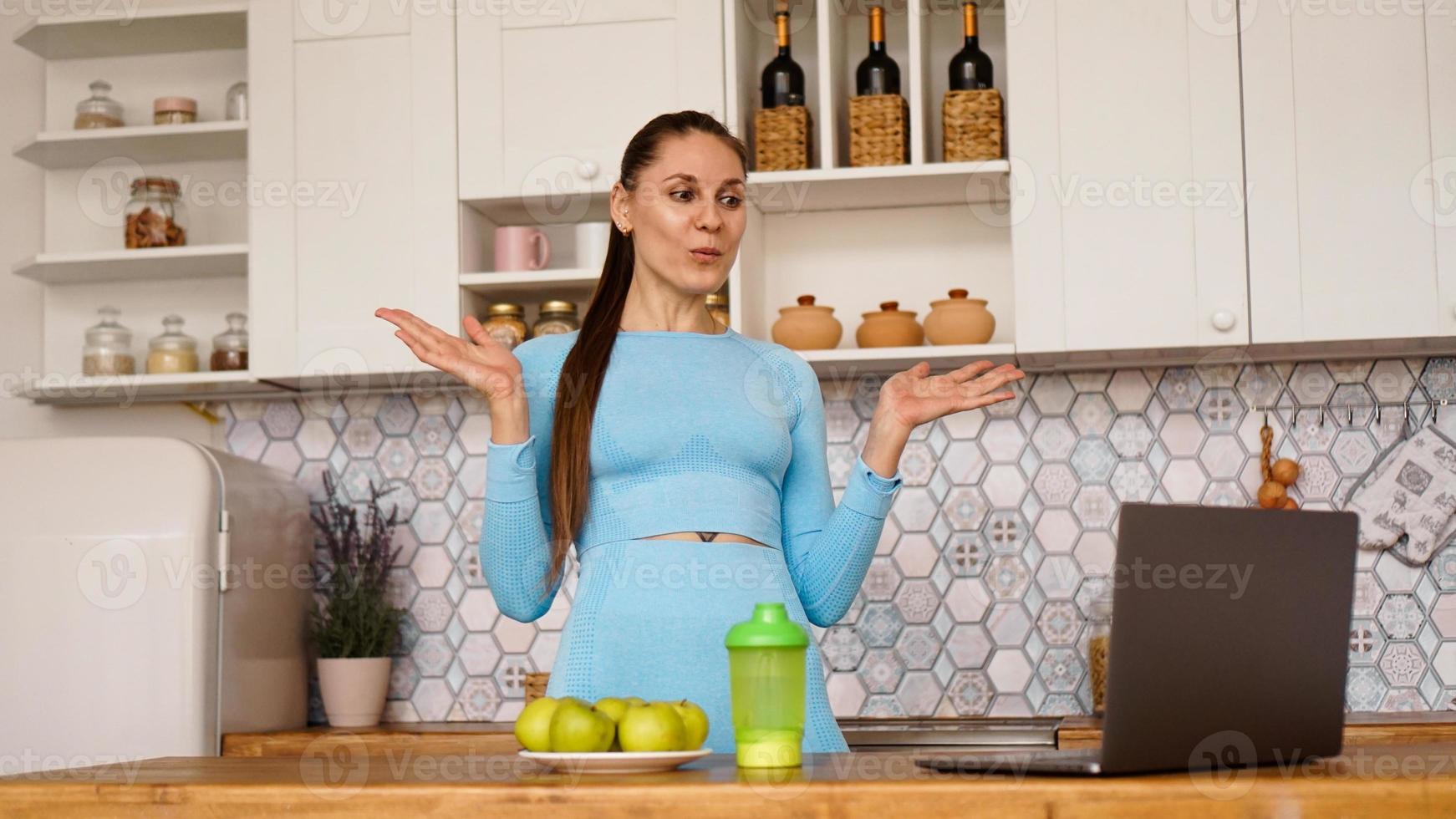 Smiling woman using computer in modern kitchen photo