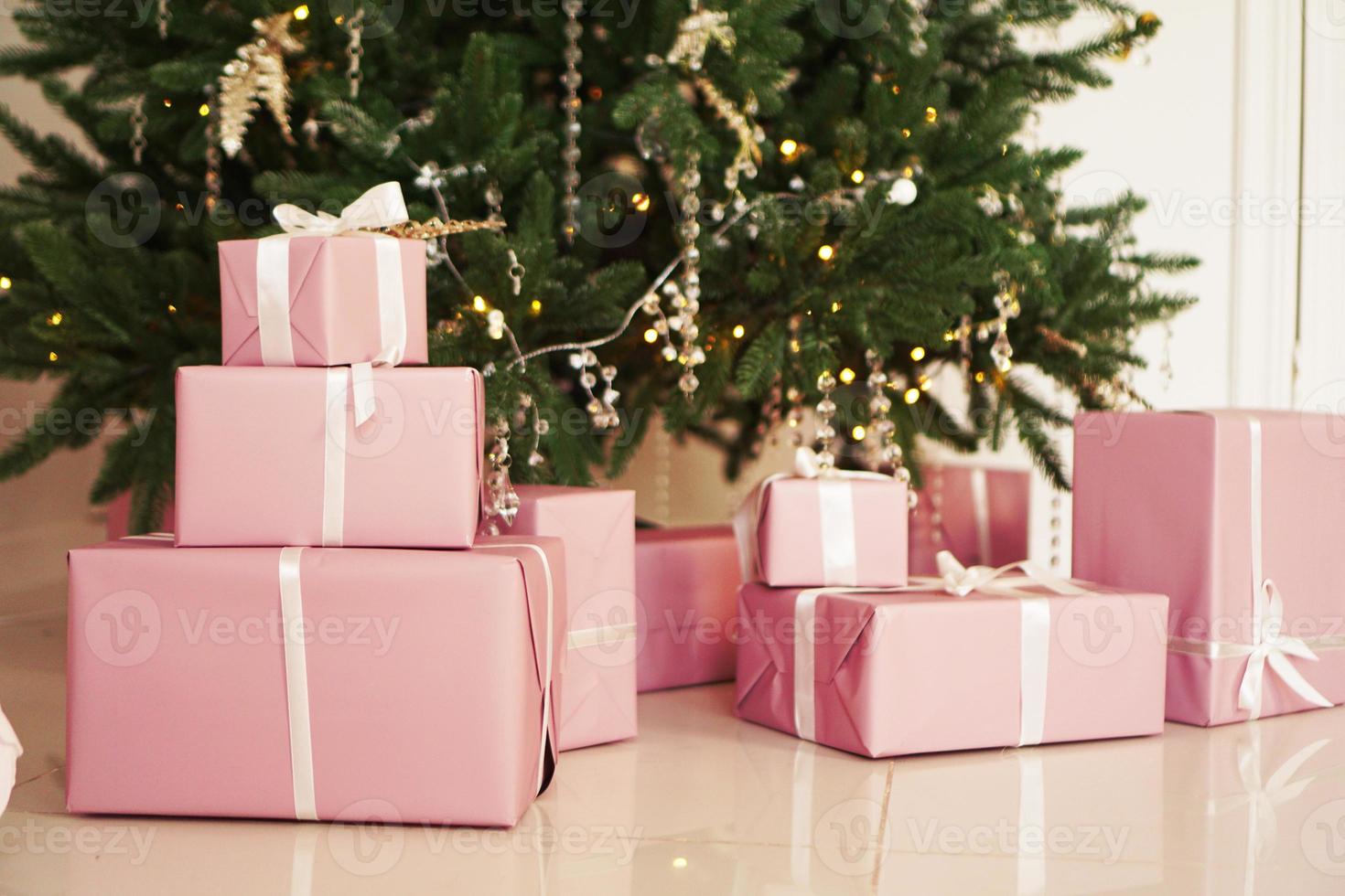 cajas de regalo rosa con cintas debajo del árbol de navidad foto