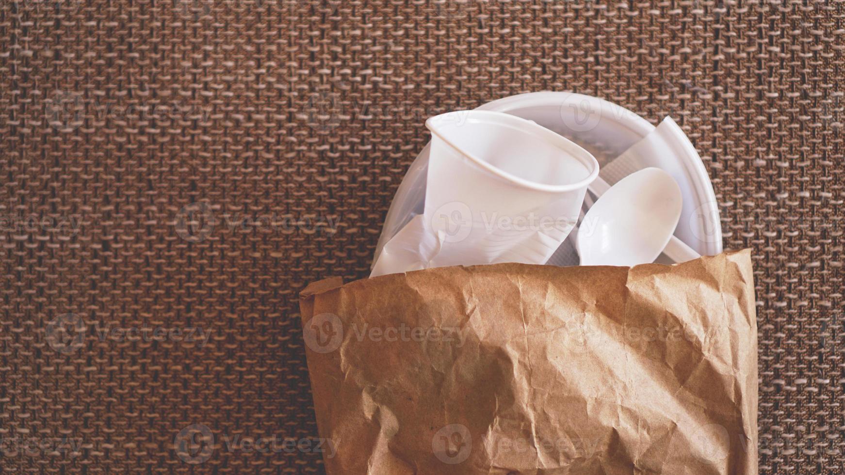 Platos de plástico blanco arrugado en un paquete de papel sobre fondo beige foto