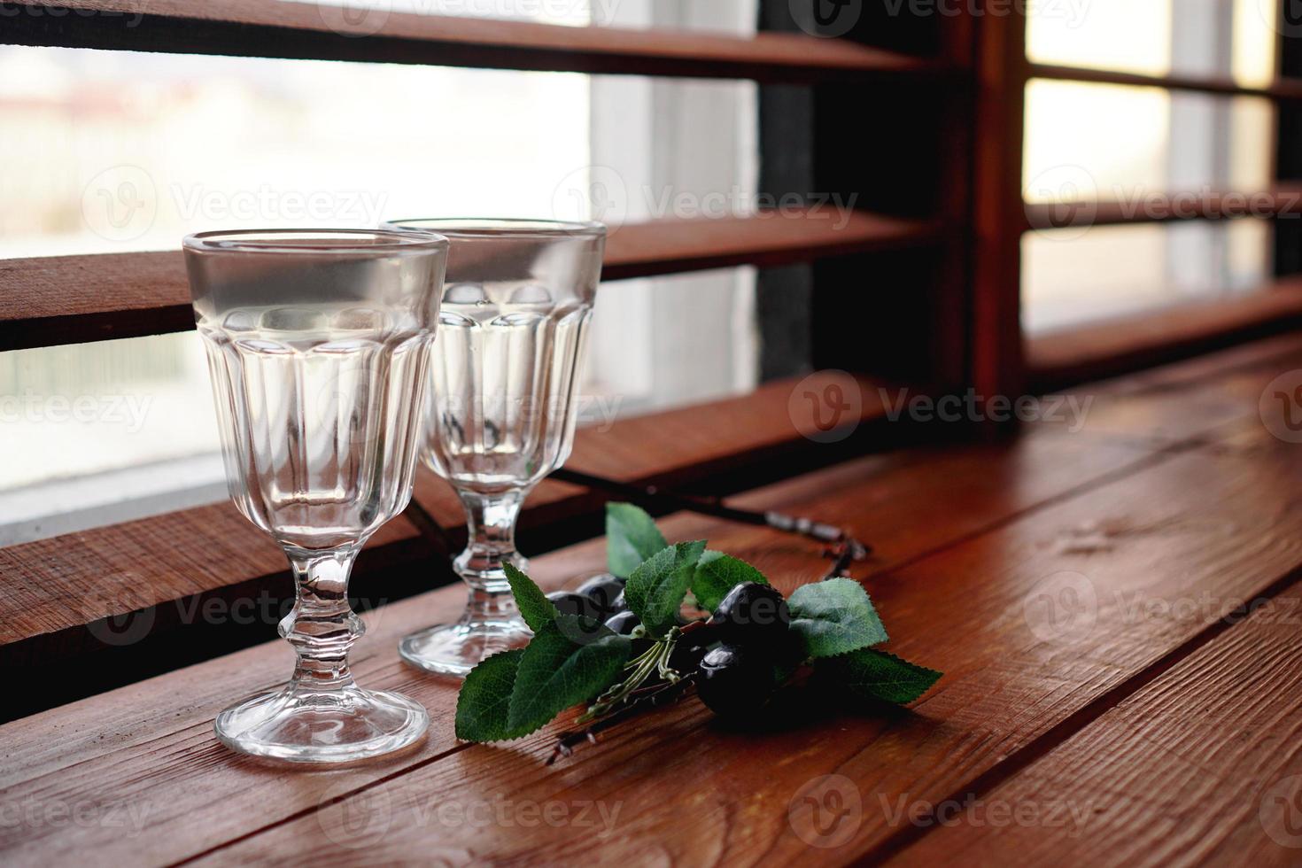 Ventana con un acogedor alféizar de madera, vasos vacíos y decoración floral. foto