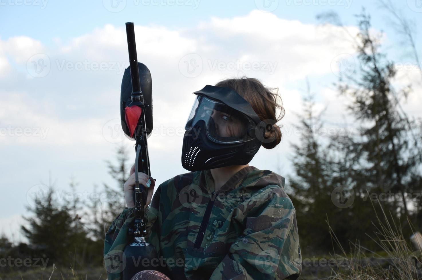 Paintball sport player girl in protective camouflage uniform and mask photo