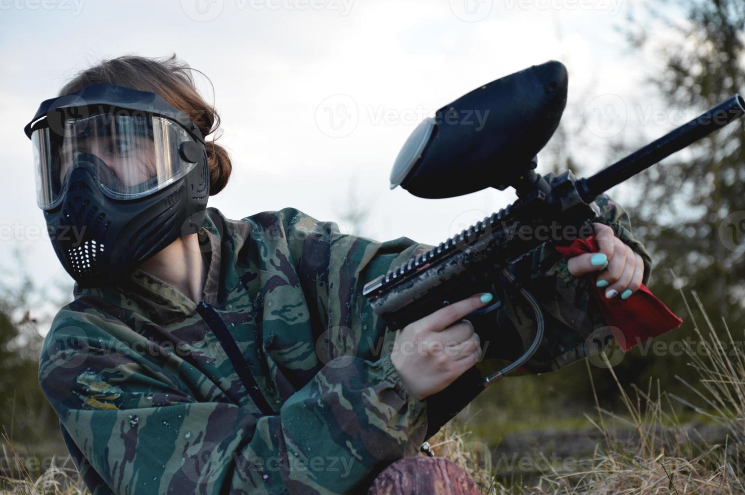 Chica de jugador de deporte de paintball en uniforme de camuflaje protector y máscara foto