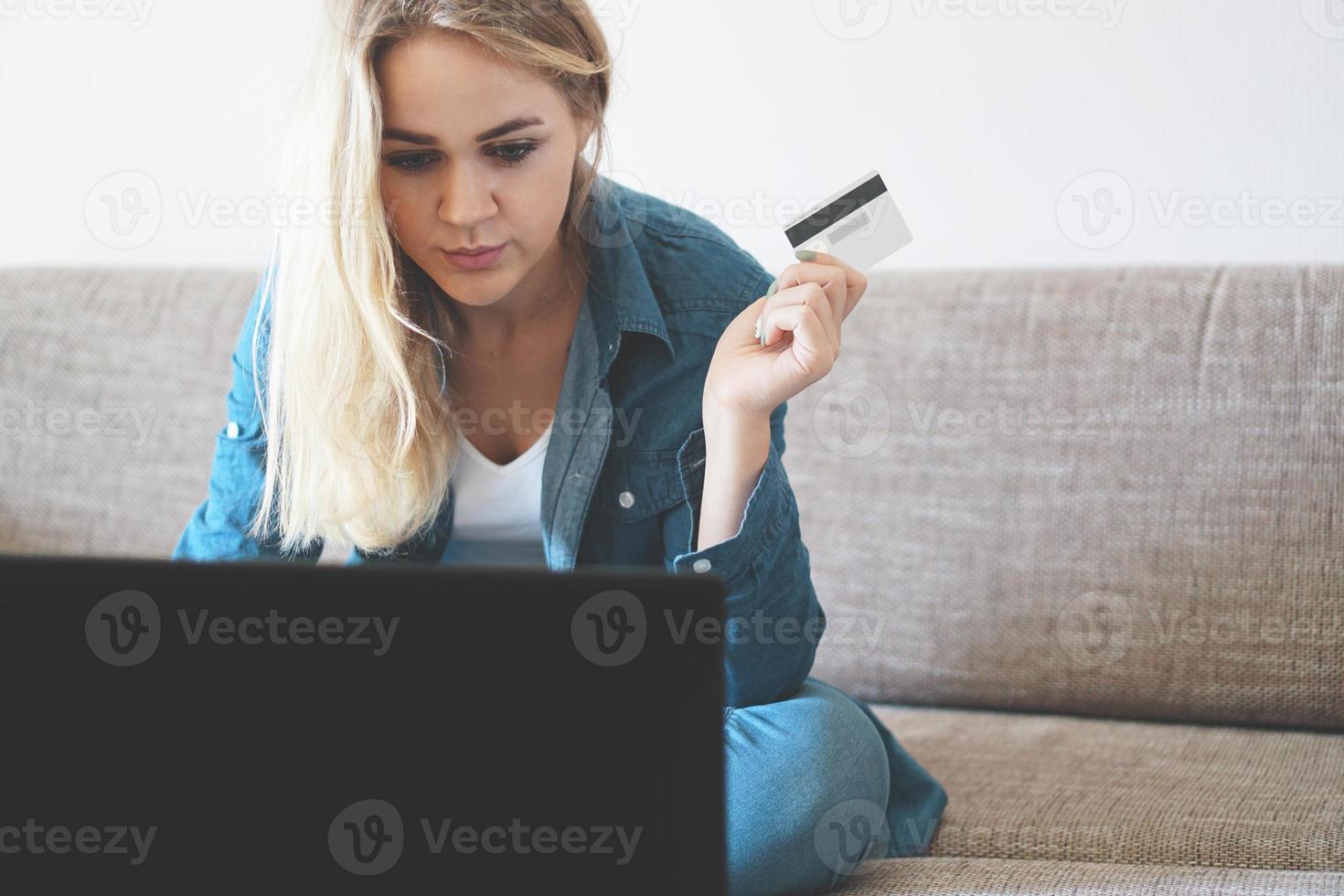 Young pretty woman working with laptop and credit card at home photo
