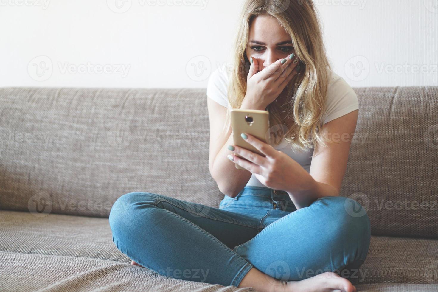 Shocked young woman looking at smartphone screen photo