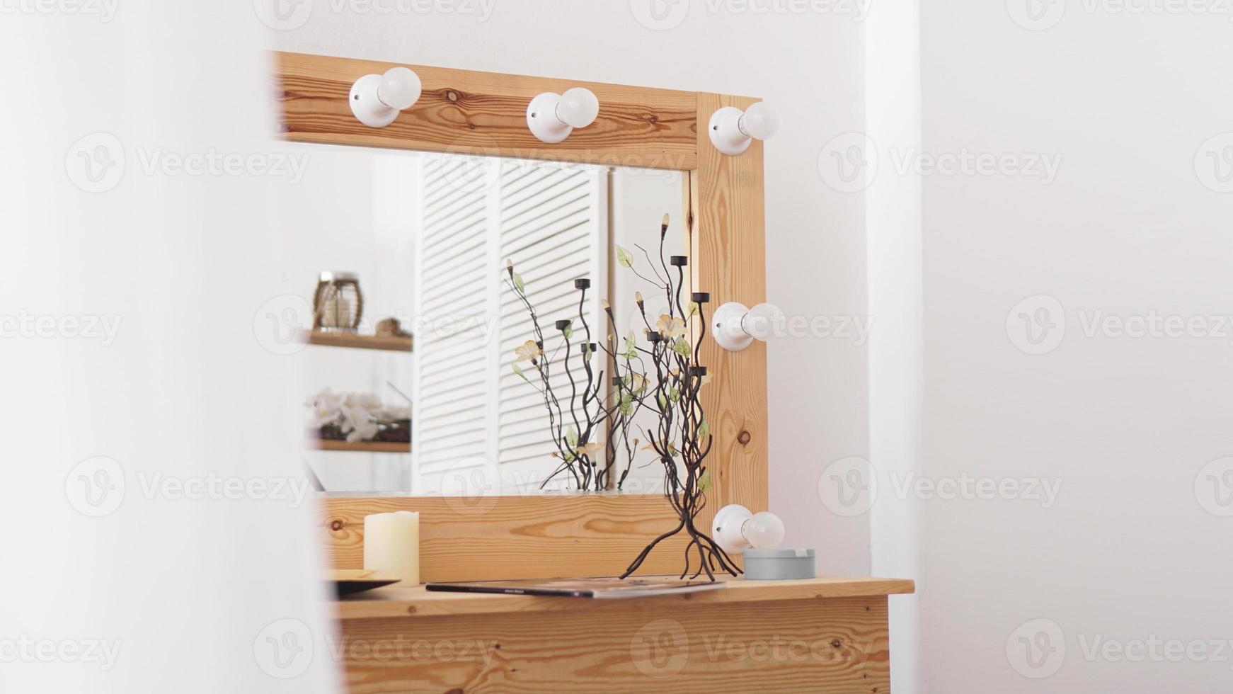 Table with makeup products and mirror near white wall photo