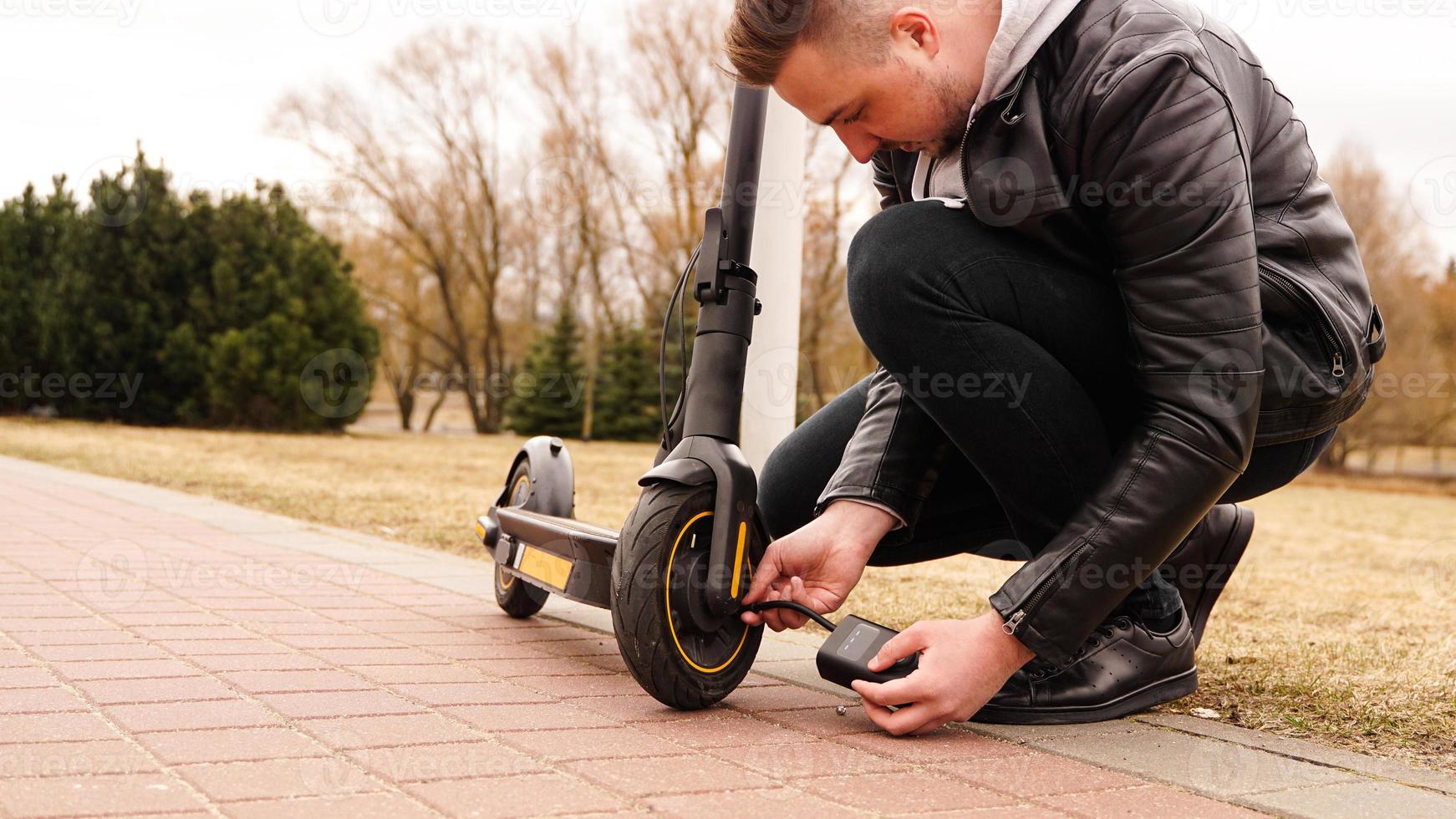 A man pumps air into the wheel of an electric scooter photo