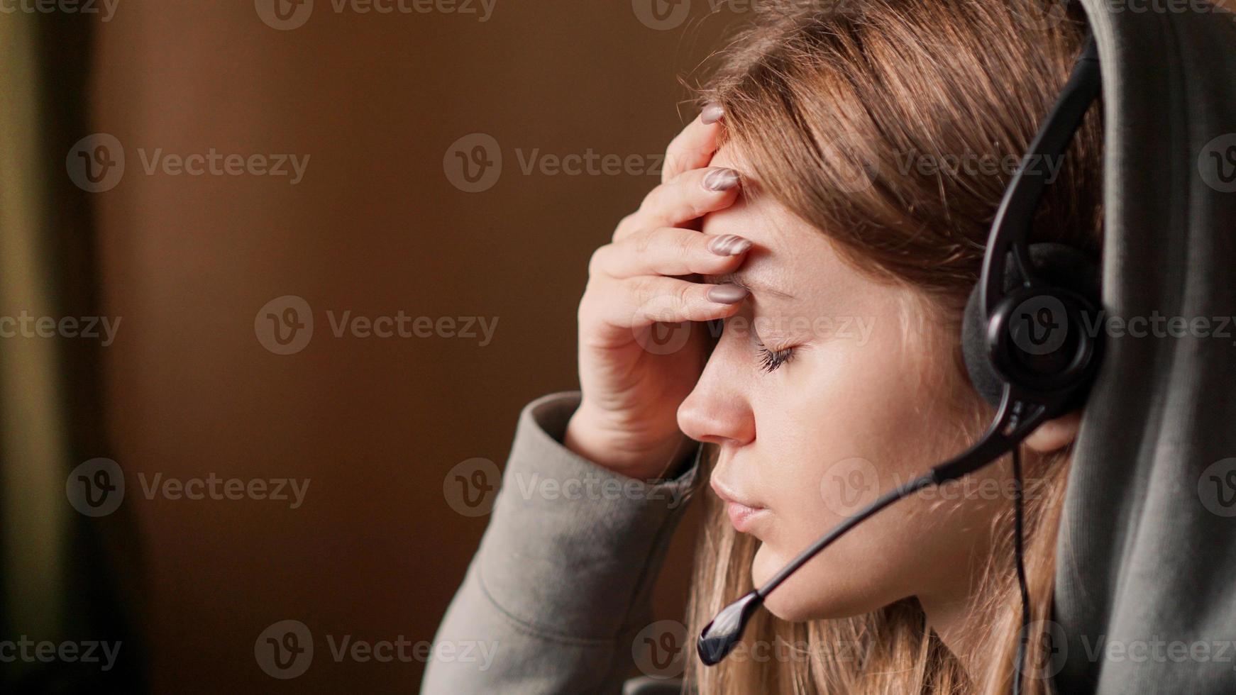 Portrait of young girl in a hoodie and with a headset. Tired photo