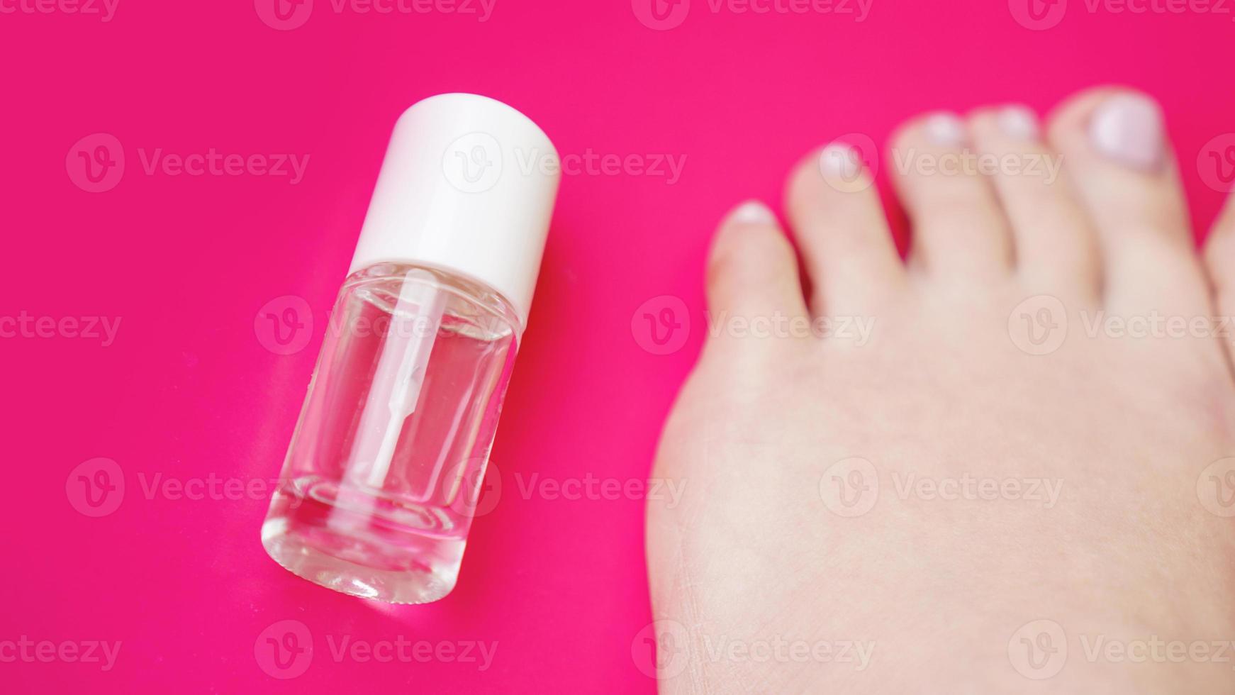 Pedicure with transparent nail polish on pink background photo