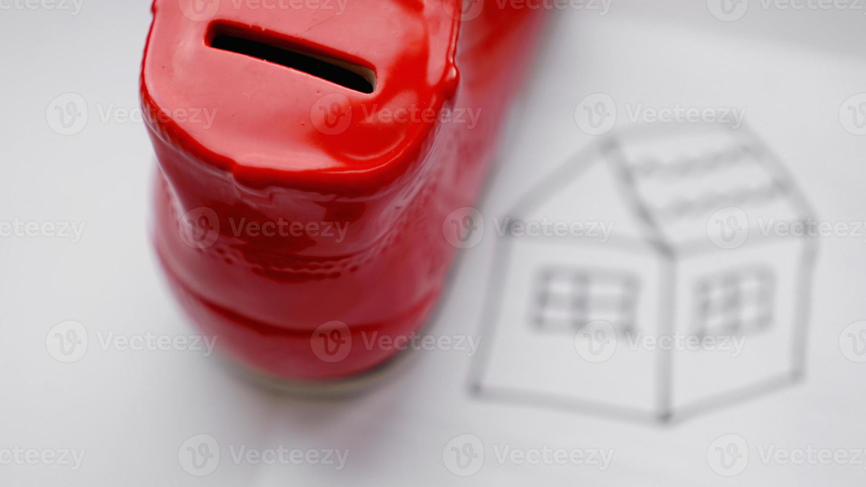 Hand dropping coin into the moneybox. Drawing a house photo