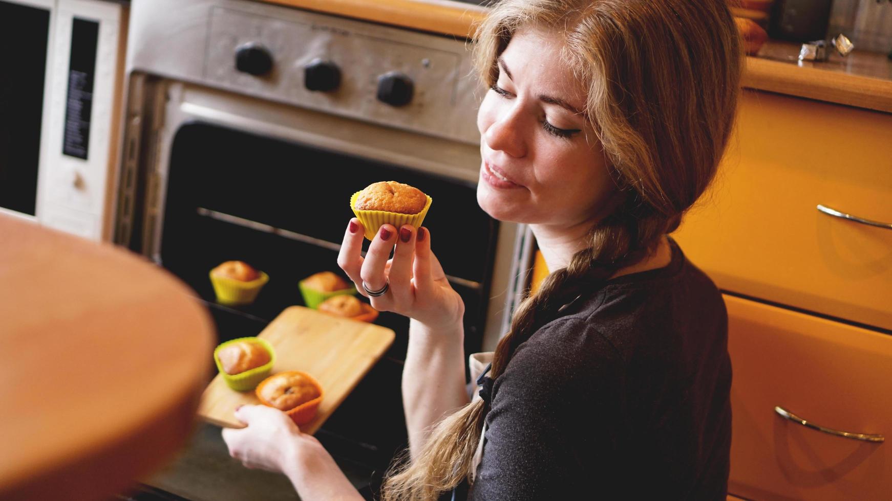 Hermosa mujer rubia mostrando muffins en una cocina foto