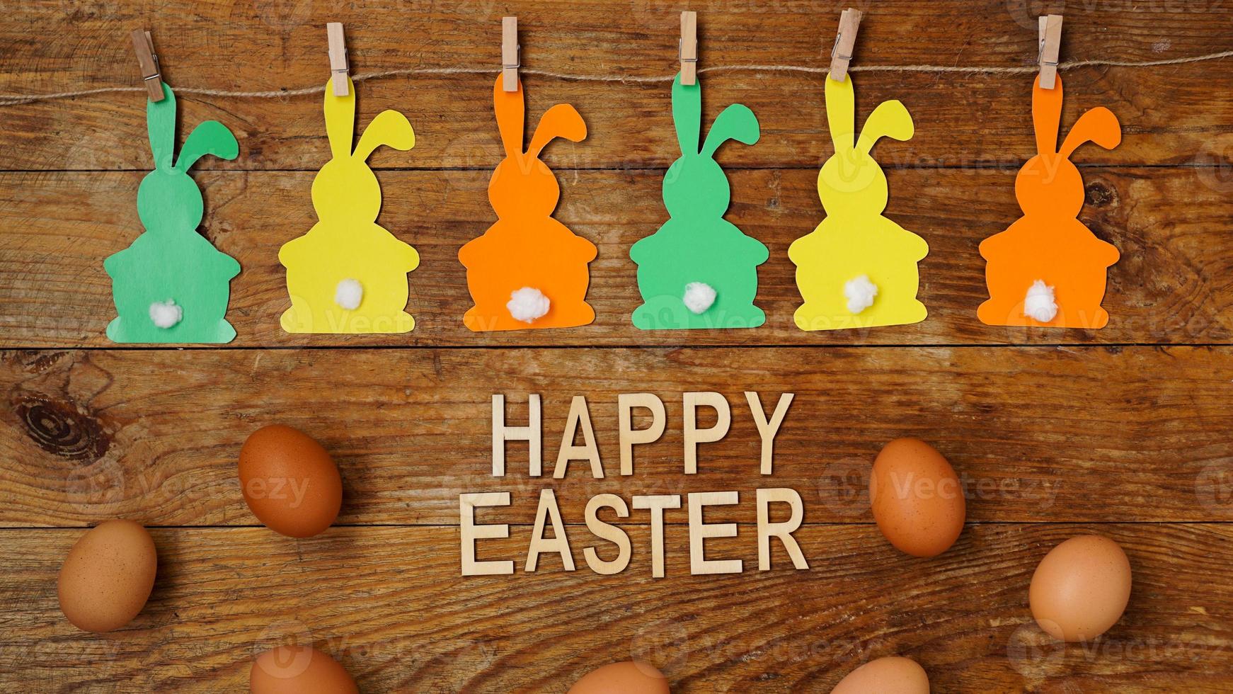 Happy Easter background. Garland of paper rabbits on a wooden photo