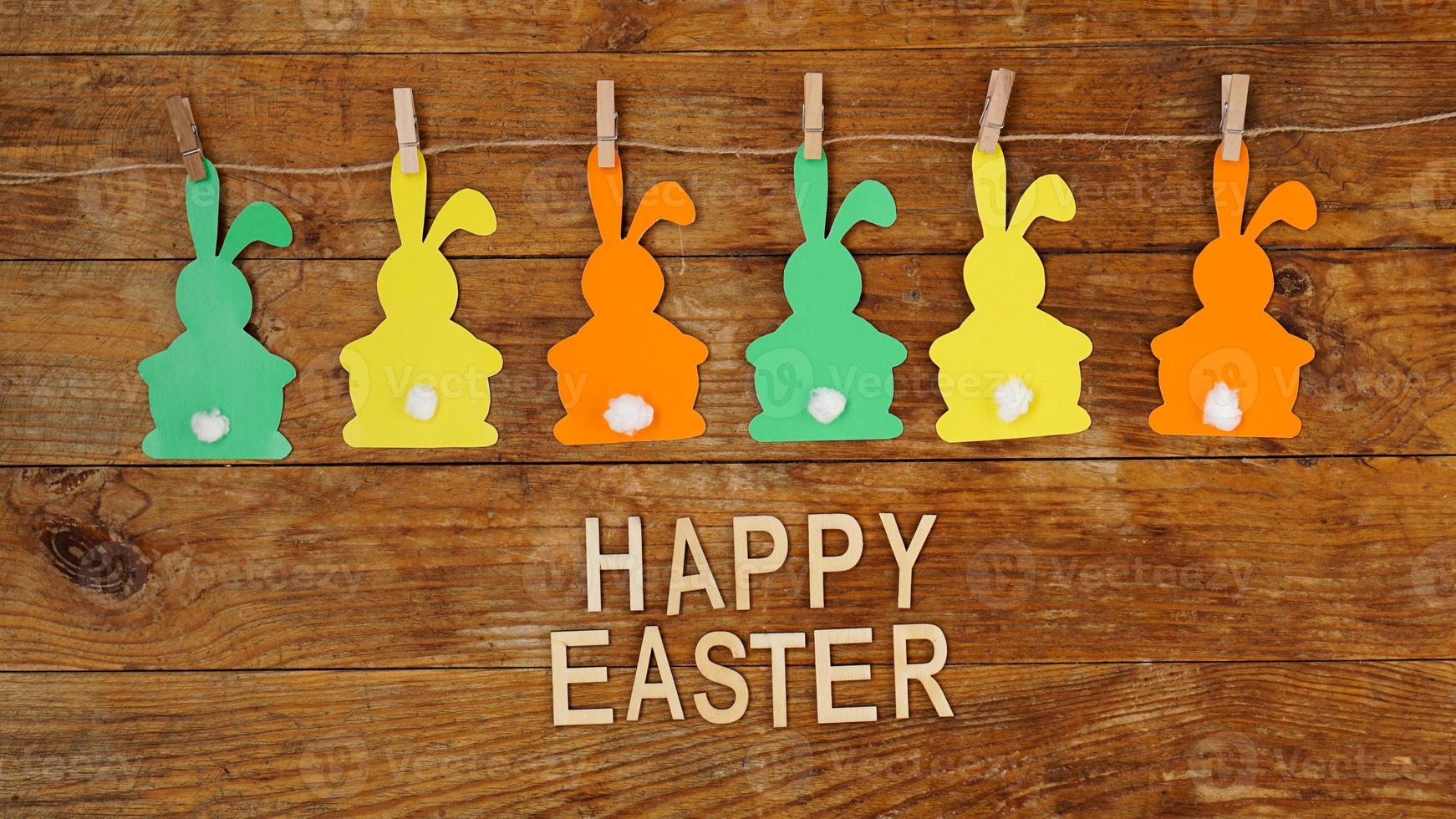 Happy Easter background. Garland of paper rabbits on a wooden photo