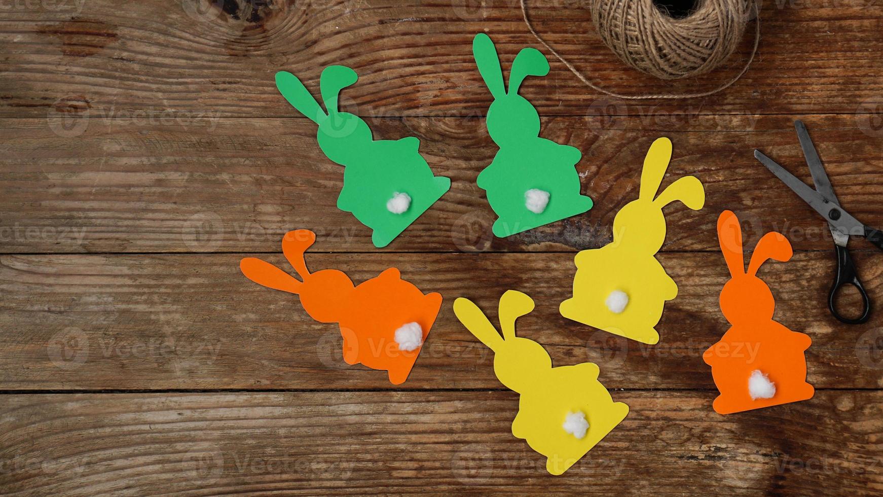 Easter bunnies made of paper on a wooden background. Create a decor photo