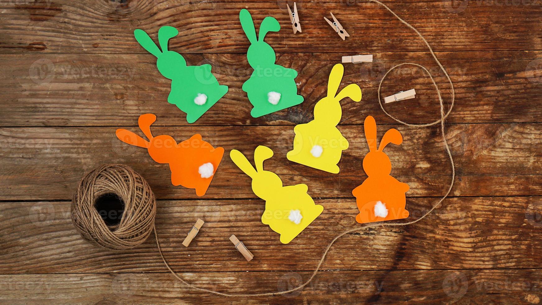 Easter bunnies made of paper on a wooden background. Create a decor photo