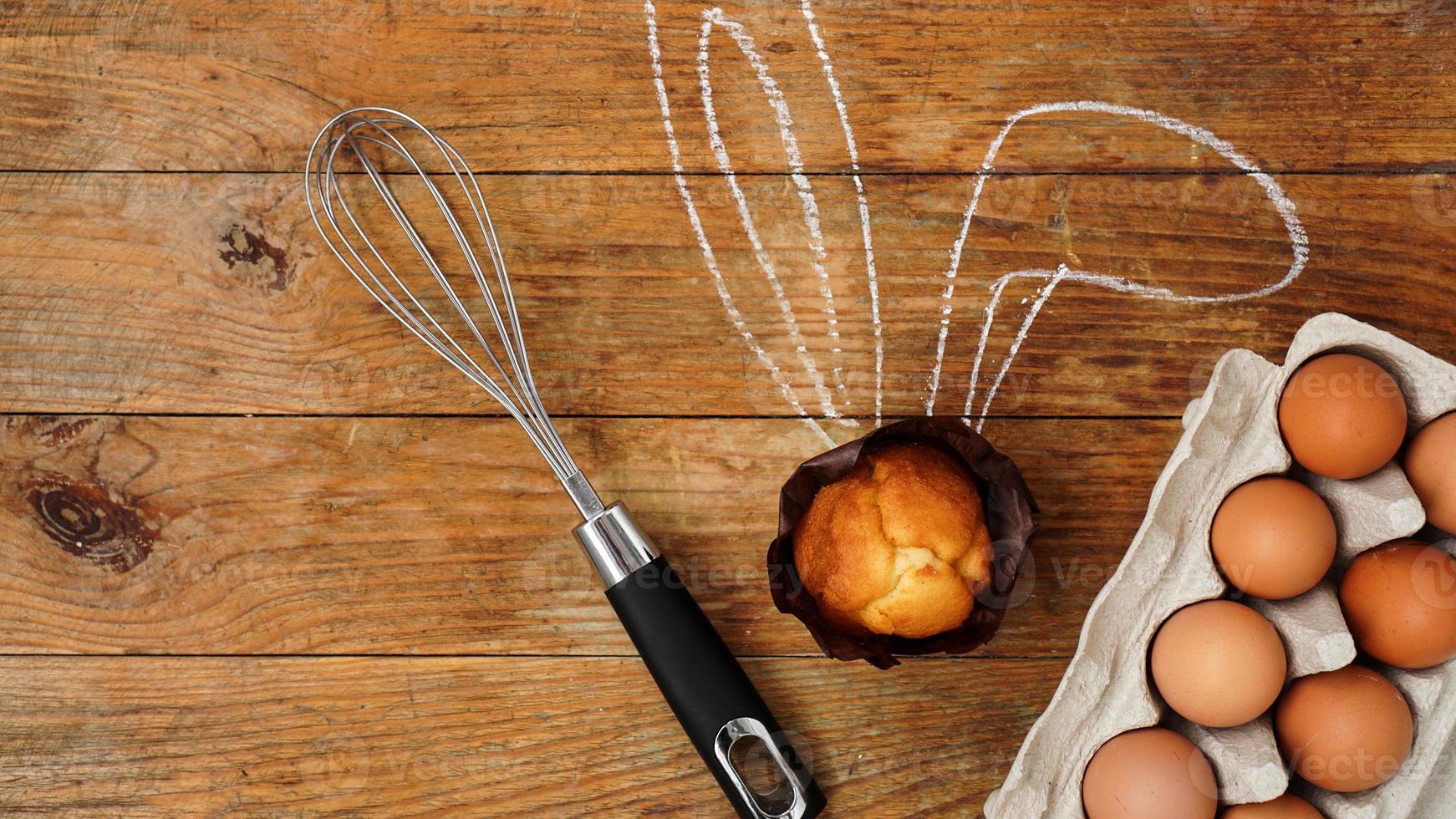 Homemade muffin with painted rabbit ears. Muffin and eggs on a wooden photo