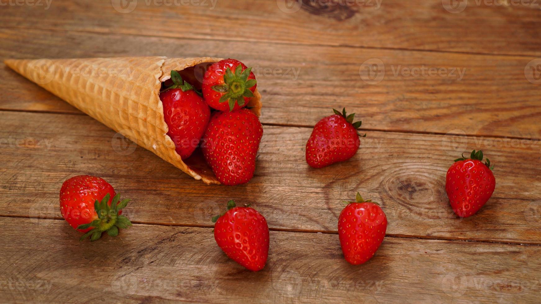 Ice cream cone with strawberries on a wooden background photo