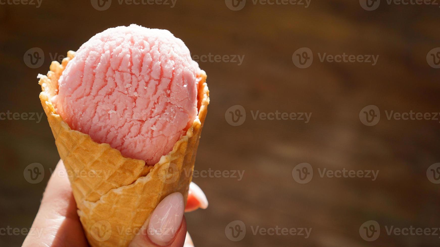 Close up image of woman hand holding raspberry ice cream photo