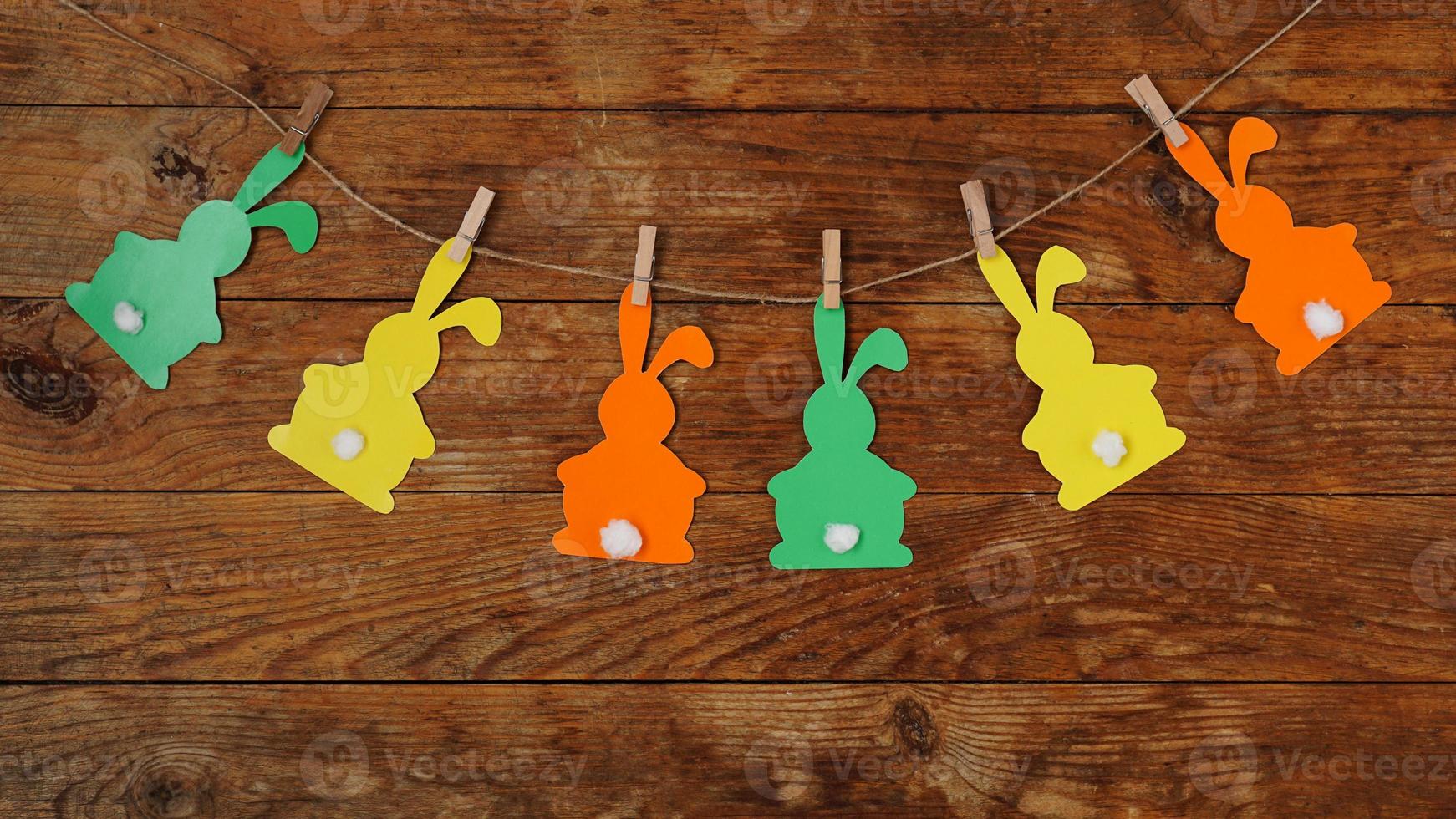 Easter background. Garland of paper rabbits on a wooden background. photo