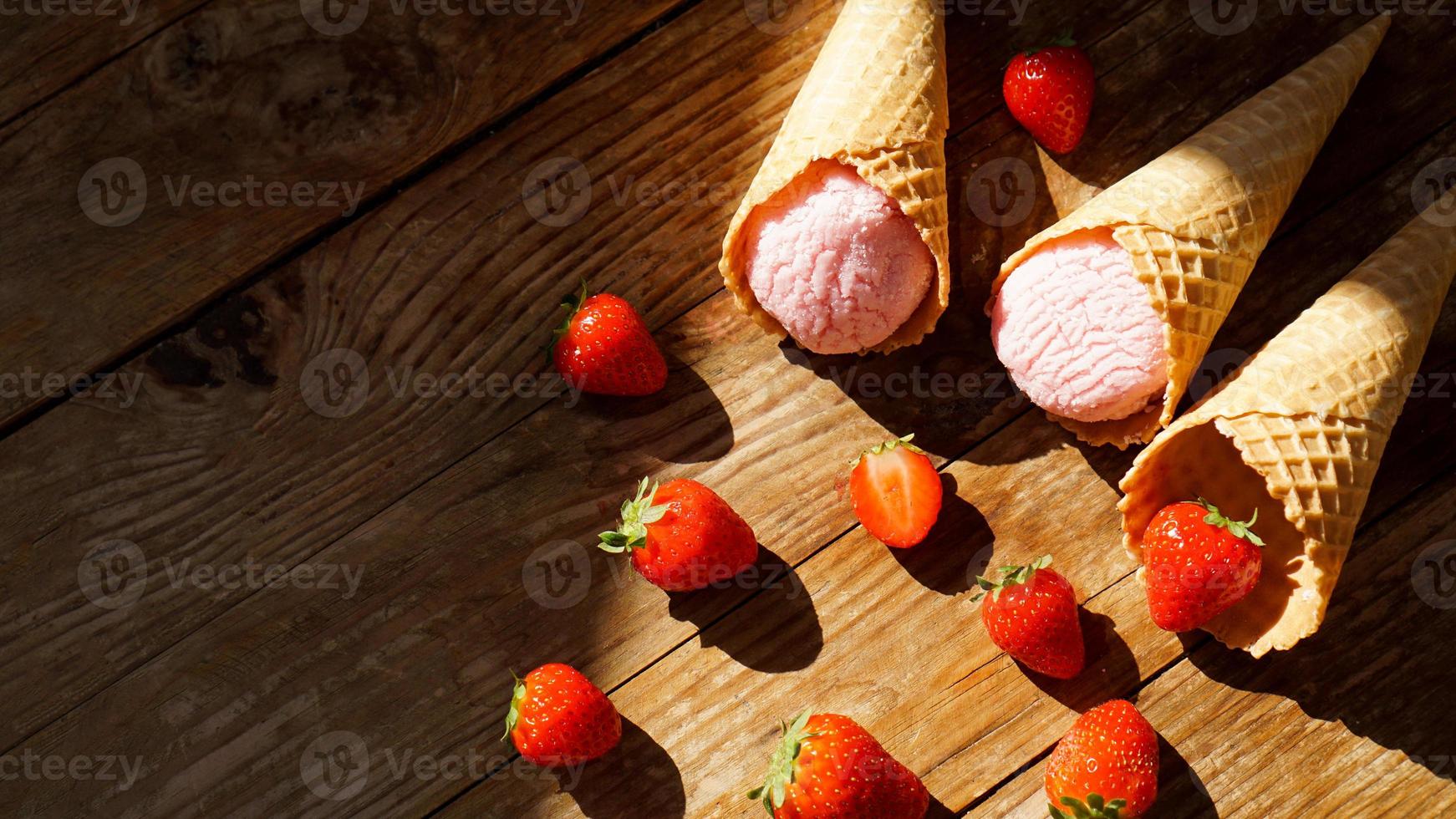 helado de fresa en un cono de galleta. frutos rojos y bolas de helado foto