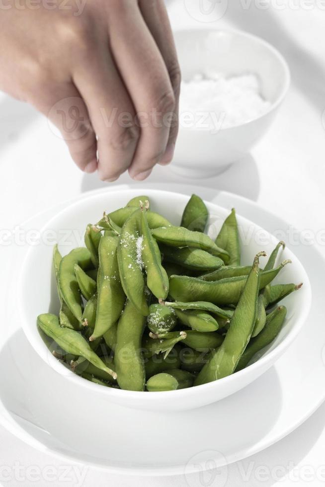 Snack de frijoles edamame orgánicos en un recipiente sobre la mesa con sal marina foto