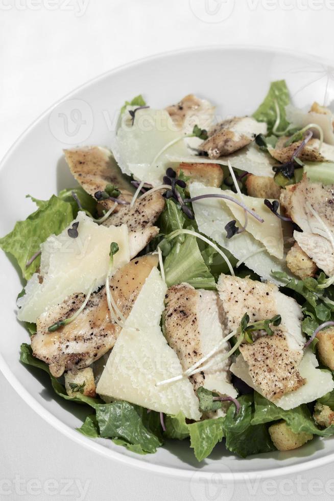 Organic chicken caesar salad with parmesan cheese and croutons on white table background photo