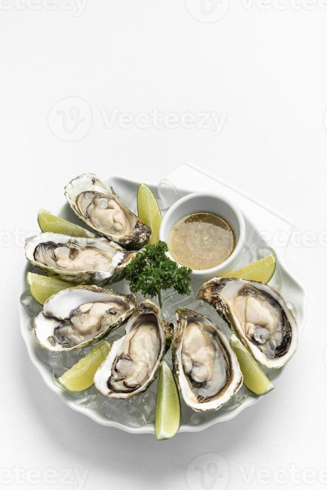 seis ostras frescas con rodajas de lima y salsa de chile picante tailandesa foto