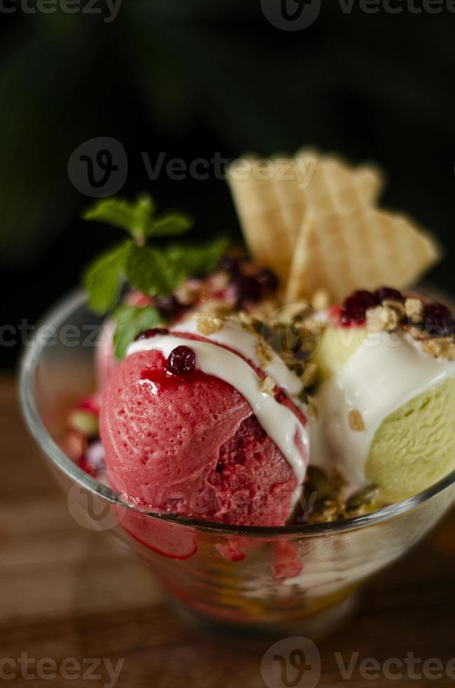 Helado de helado de fresa y pistacho postre en un tazón sobre la mesa de madera foto