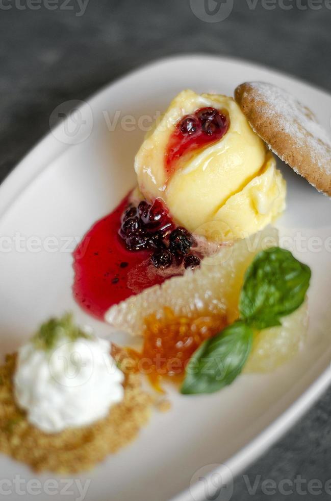 Helado de mango orgánico gourmet con salsa coulis de grosellas, postre en placa foto