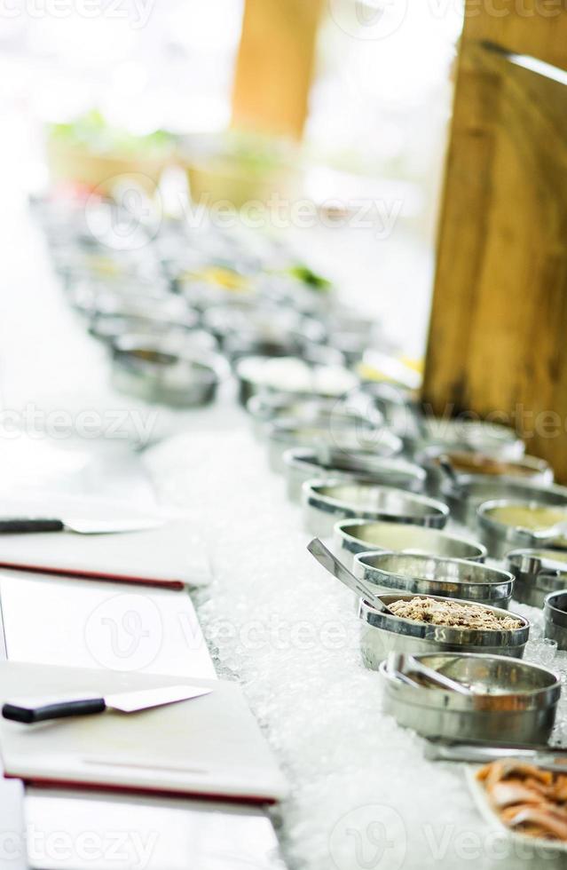 Bowls of mixed fresh organic red peppers and vegetables in modern salad bar display photo