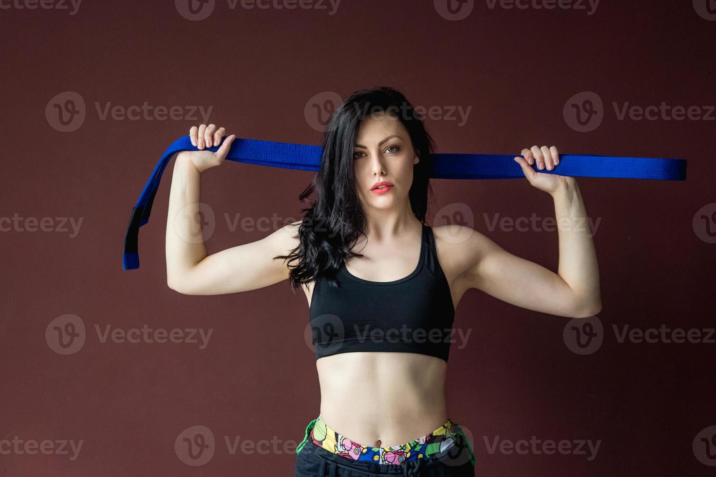 Hermosa mujer atlética con cinturón azul en el fondo de la pared foto