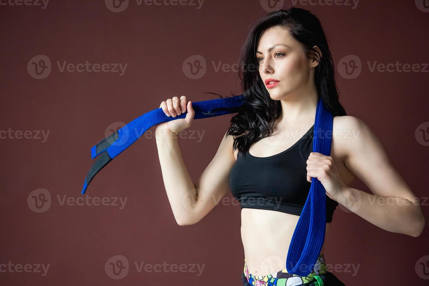 Hermosa mujer atlética con cinturón azul en el fondo de la pared foto