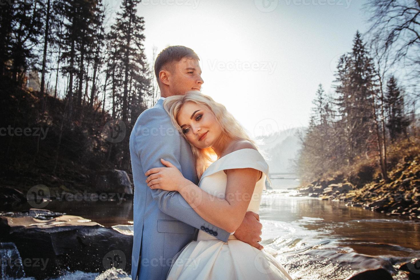 novios en un fondo de montañas y ríos en las puestas de sol foto