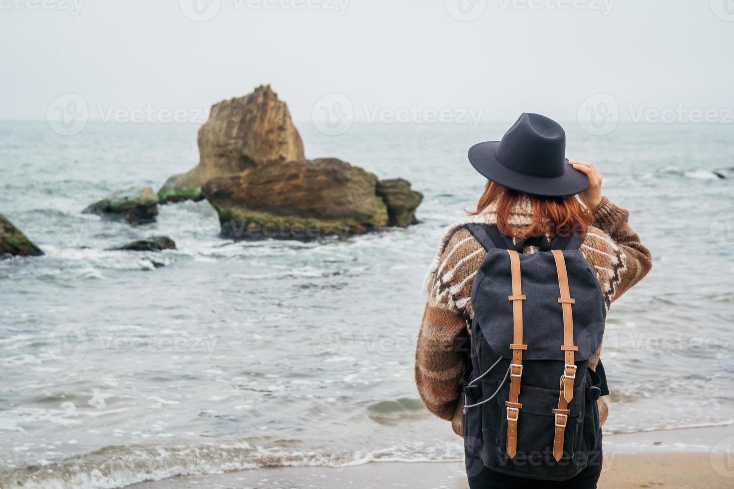 Mujer con sombrero y mochila en la playa sobre un fondo de mar foto