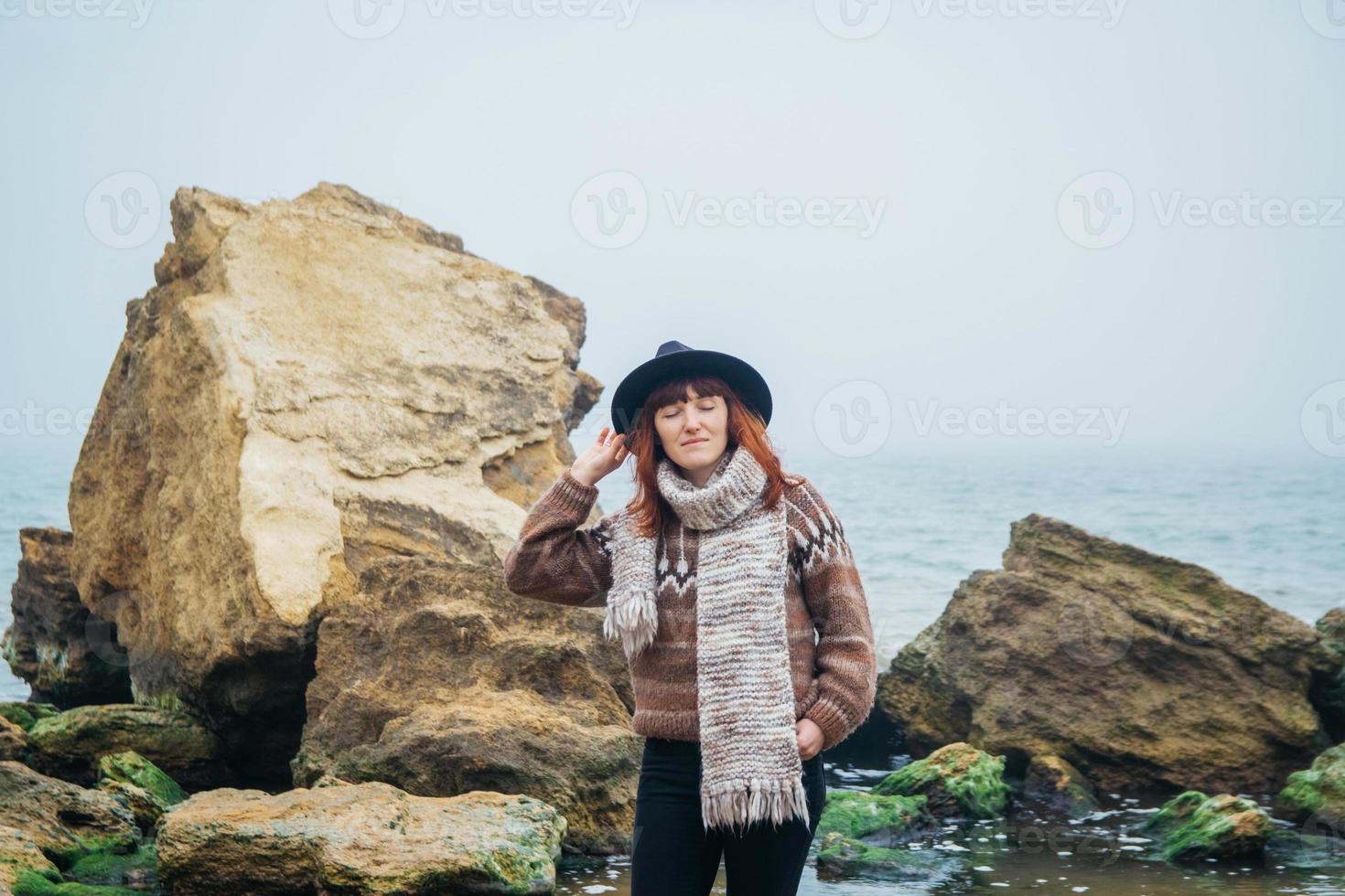 Mujer turista con sombrero con mochila sobre rocas sobre un fondo de mar foto