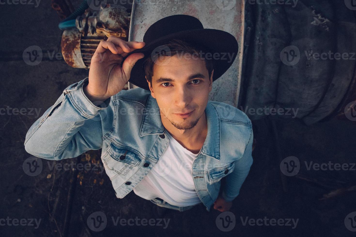 Hombre con sombrero vestido con jeans en el fondo antiguo edificio abandonado foto