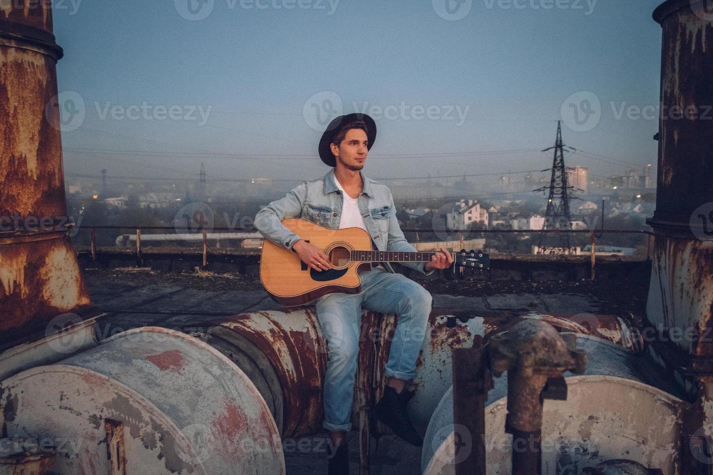 El hombre tocando la guitarra con sombrero en el fondo antiguo edificio abandonado foto