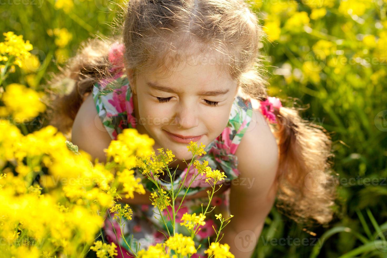 niña rubia inhala aroma de flores foto